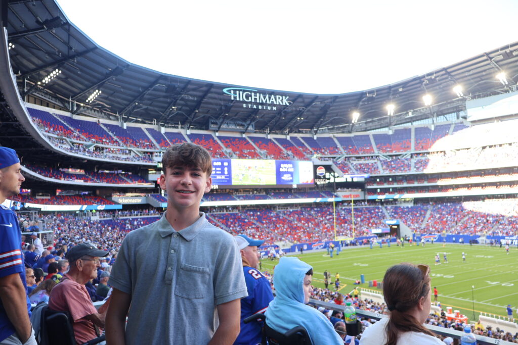A young attendee smiling in the stands with the field behind him