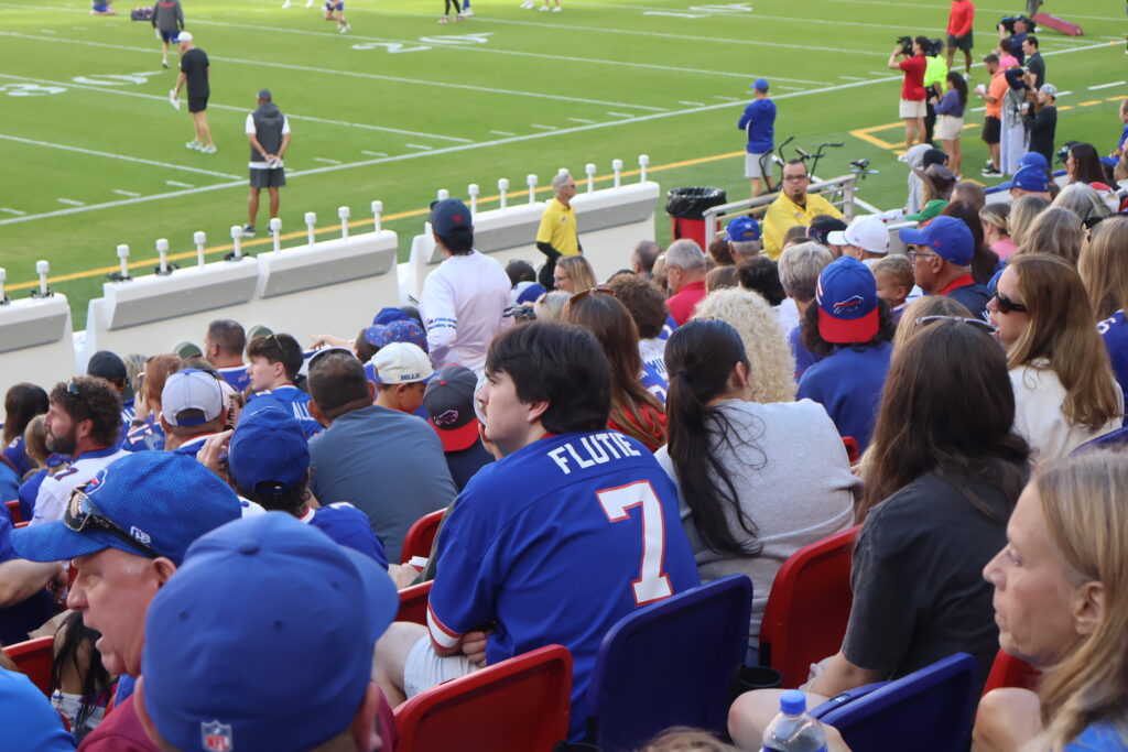 A fan in a Flutie number 7 jersey watching players on the field