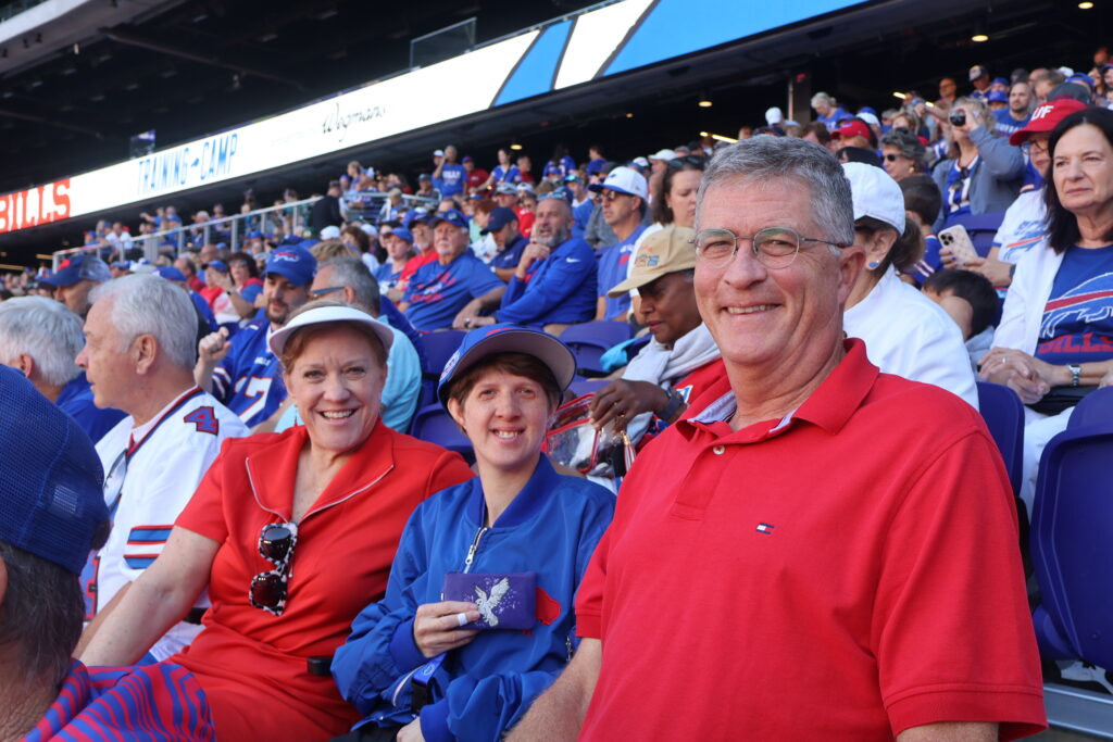 Three attendees smiling together in the stands