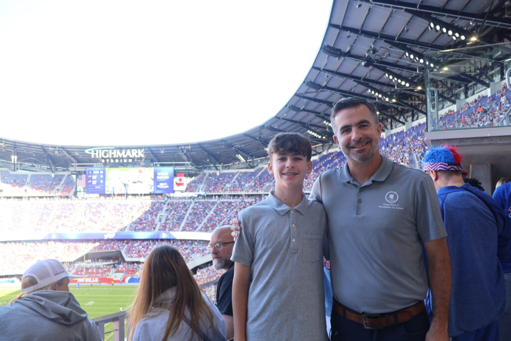 Two attendees posing with the stadium bowl behind them
