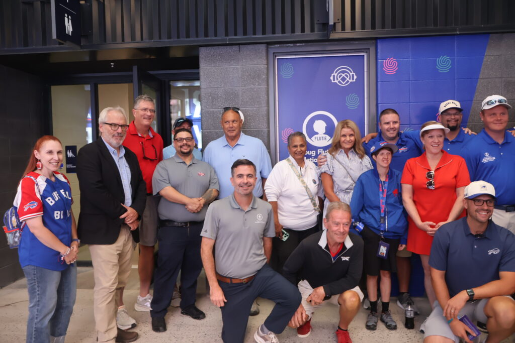 Attendees and stadium staff posing together at the sensory room opening