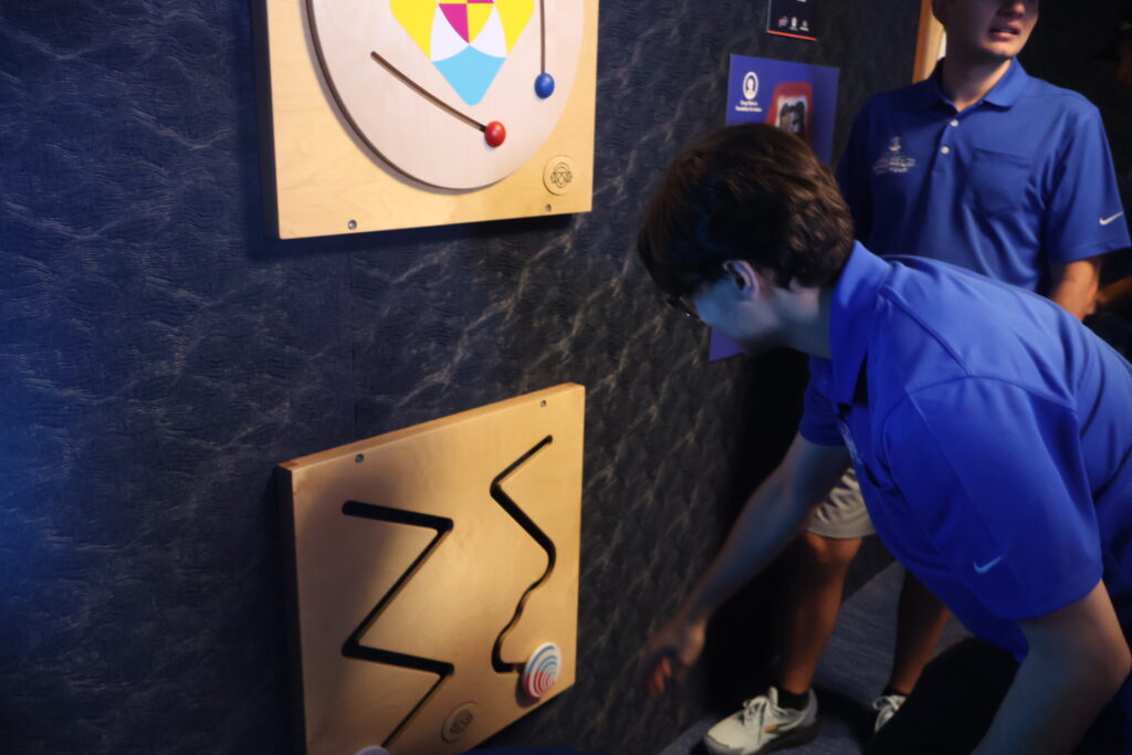 A young visitor trying a tactile wall puzzle in the sensory room