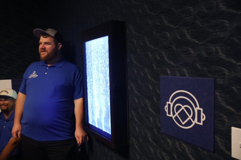 A staff member beside an illuminated sensory panel on the wall