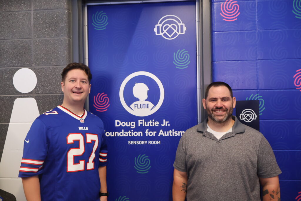 Two men smiling beside the Foundation's sensory room banner