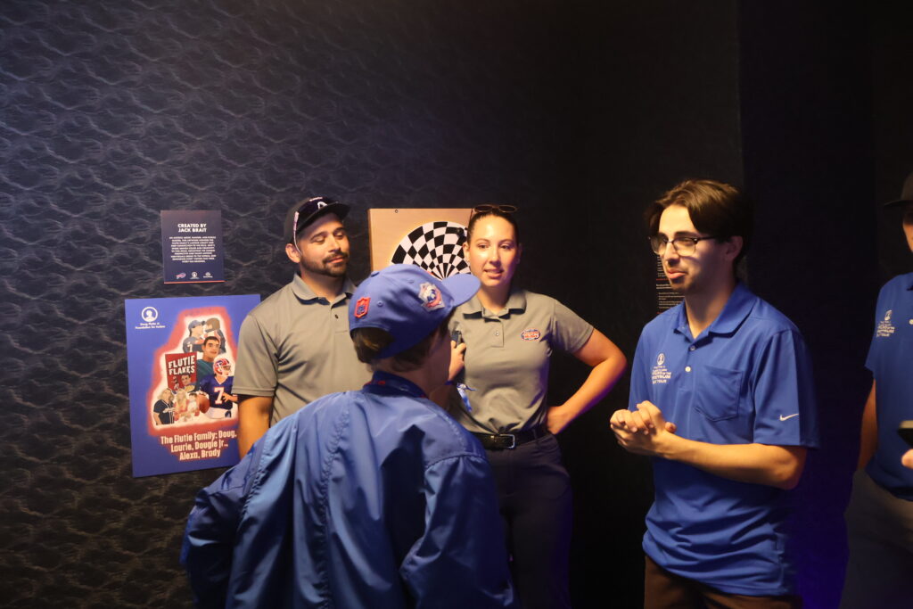 Four people talking in the sensory room next to a Flutie Flakes wall panel