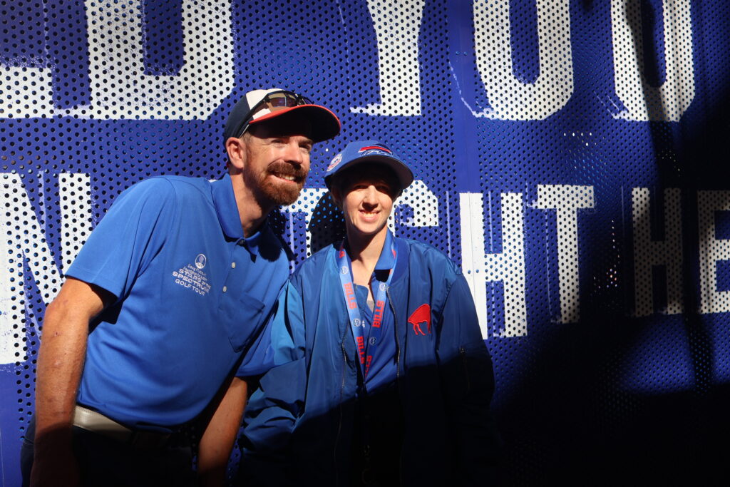 Two Foundation staff members posing against a lit stadium wall graphic