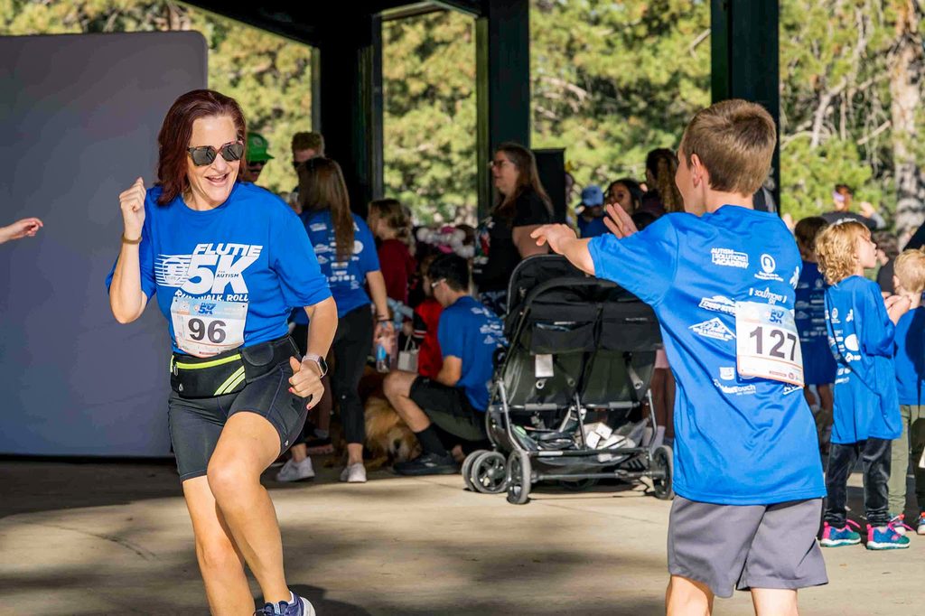 A runner and a young participant high-five under the pavilion after the race