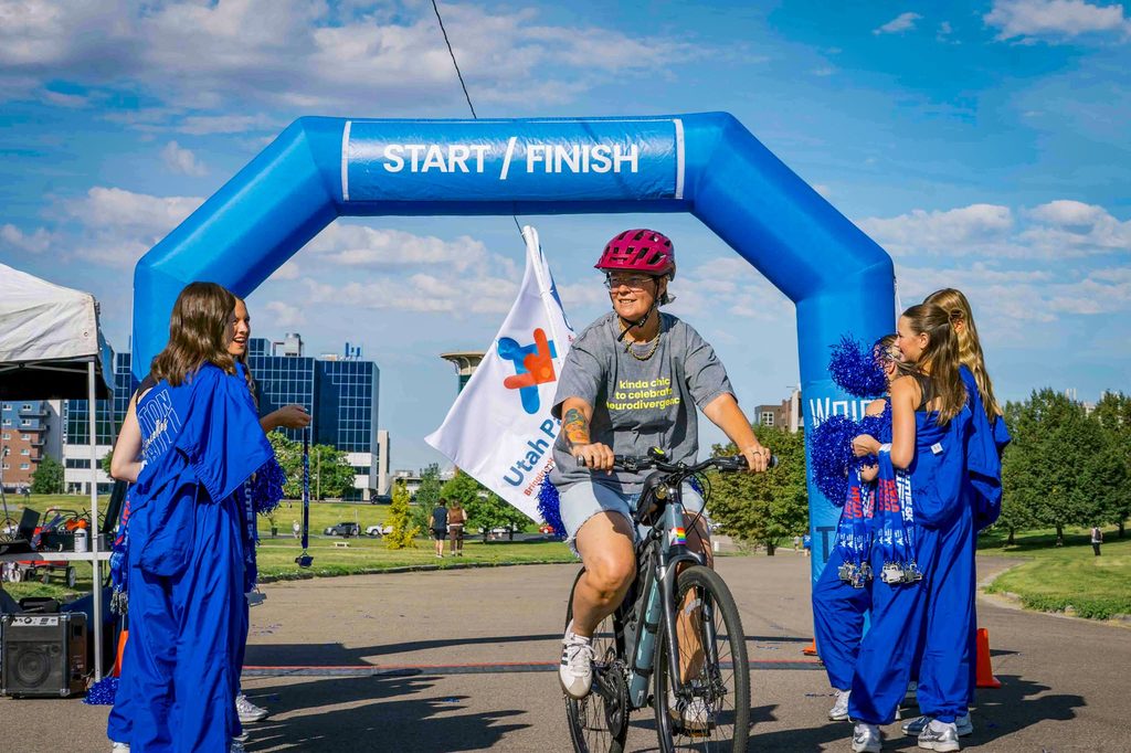 A cyclist rolling through the start and finish arch as cheerleaders line the route
