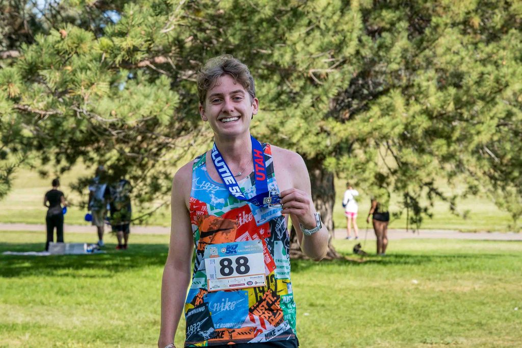 A finisher holding up a Flutie 5K Utah medal