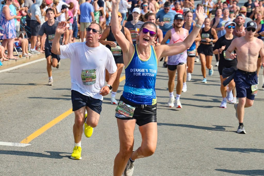 A Dougie's Team for Autism runner throws both arms wide along the final stretch