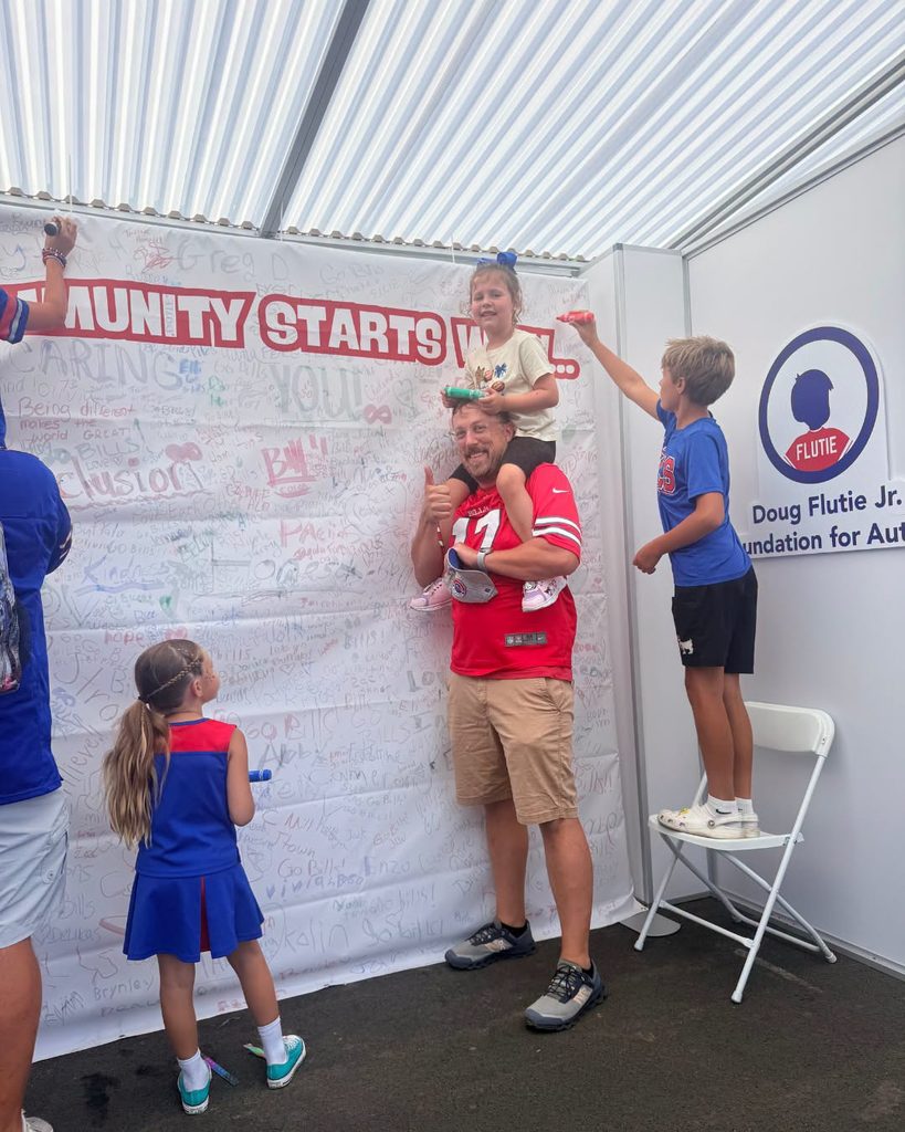 Visitors adding their names to a community signing wall at the Doug Flutie Jr. Foundation booth