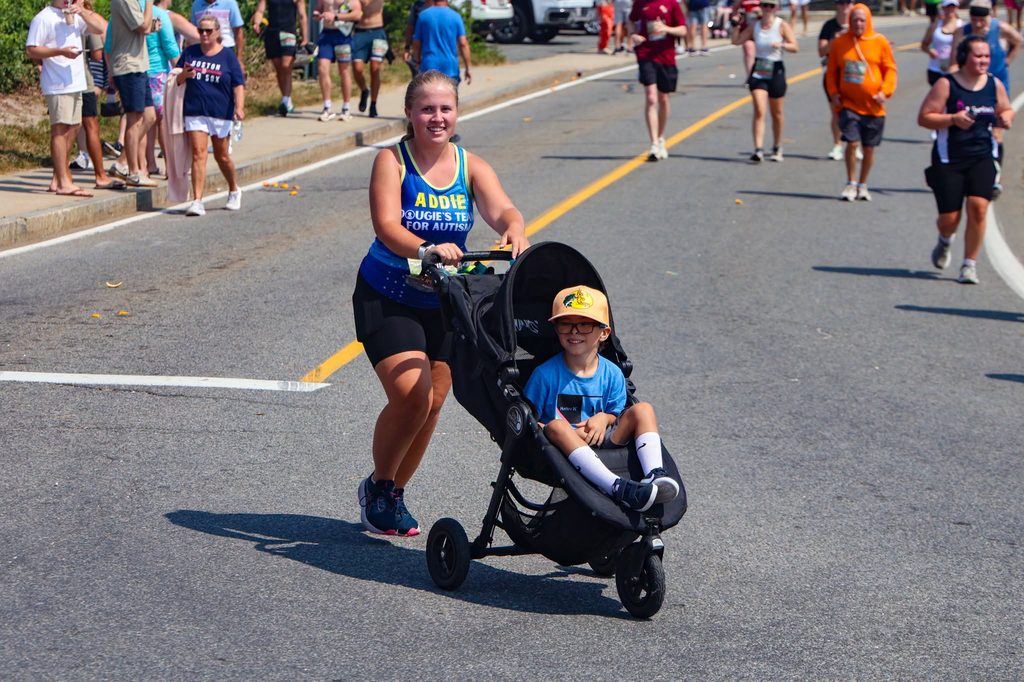 A Dougie's Team for Autism runner pushes a child in a running stroller along the route